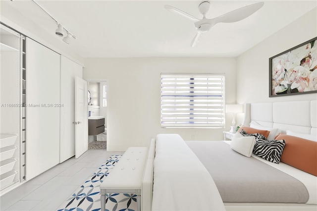 bedroom featuring ensuite bath, ceiling fan, rail lighting, a closet, and light tile patterned floors