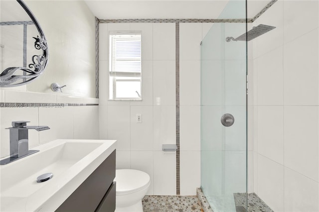 bathroom with vanity, a shower with door, toilet, and tile walls