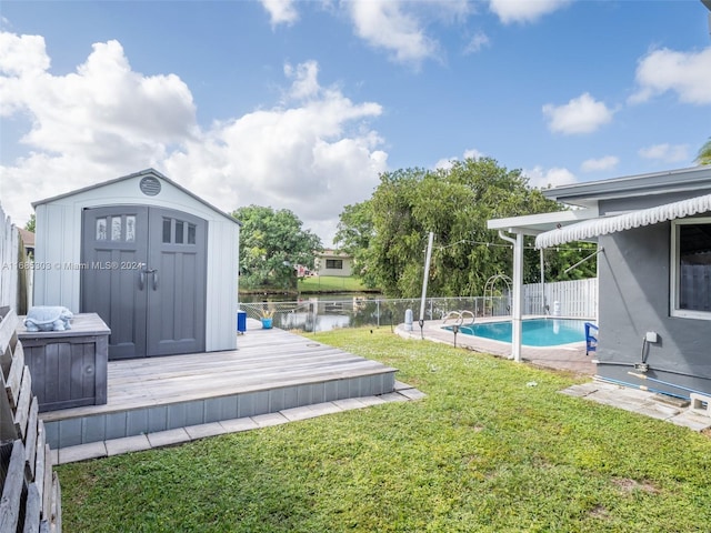 view of yard with a water view, a storage unit, and a fenced in pool