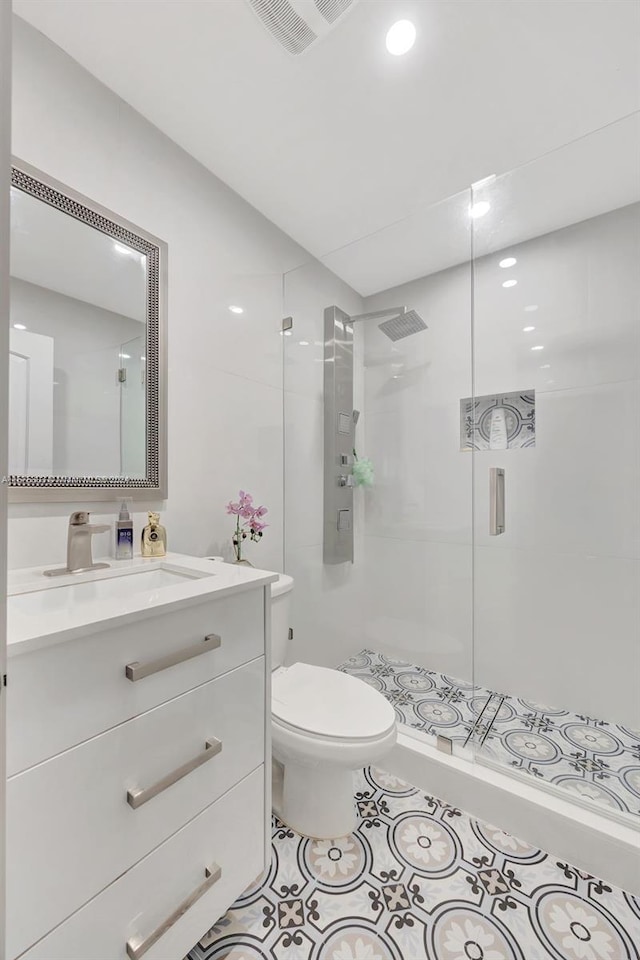 bathroom with tile patterned floors, vanity, a shower with shower door, and toilet