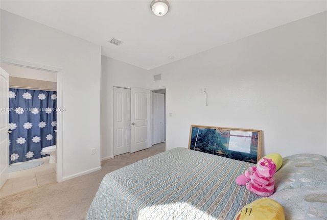 carpeted bedroom with ensuite bathroom and a closet