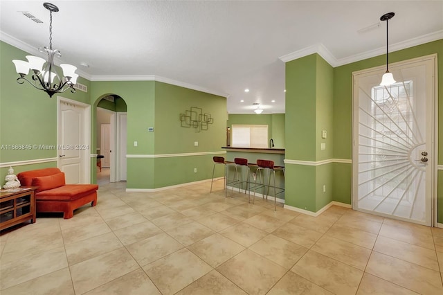 foyer entrance with crown molding, a wealth of natural light, a chandelier, and light tile patterned floors