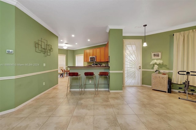 kitchen featuring a breakfast bar area, crown molding, pendant lighting, and plenty of natural light