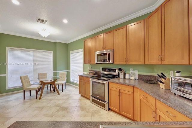 kitchen featuring crown molding, a textured ceiling, appliances with stainless steel finishes, and light tile patterned flooring