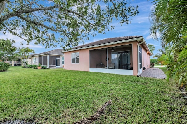 back of property featuring a patio, a sunroom, a lawn, and ceiling fan