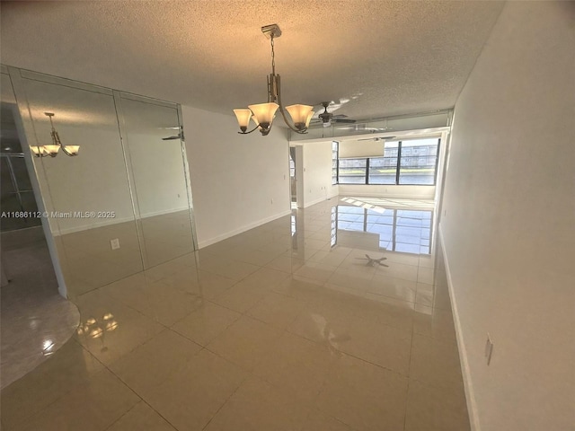 tiled empty room featuring ceiling fan with notable chandelier and a textured ceiling