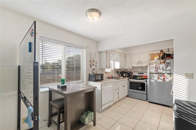 kitchen featuring a textured ceiling, light tile patterned flooring, under cabinet range hood, stainless steel appliances, and a sink