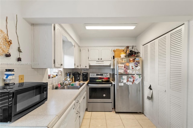 kitchen with under cabinet range hood, a sink, white cabinets, appliances with stainless steel finishes, and tasteful backsplash