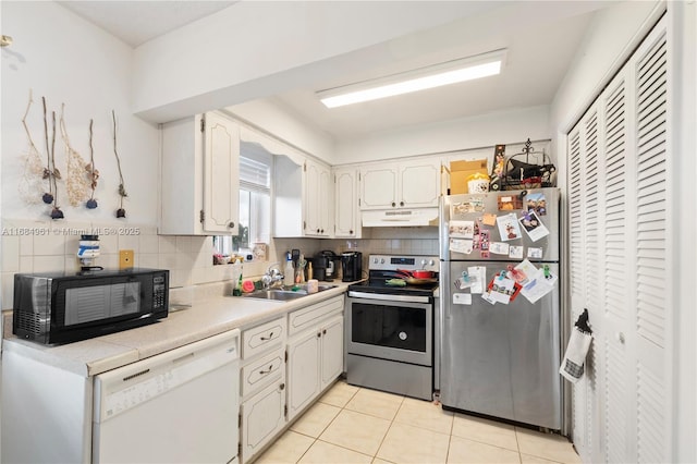 kitchen with under cabinet range hood, backsplash, stainless steel appliances, and a sink