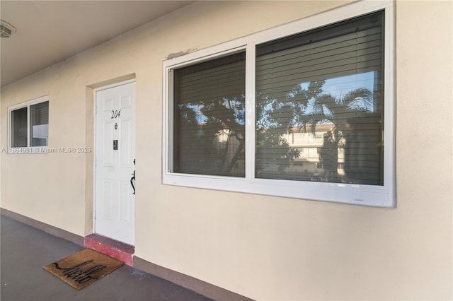 property entrance with visible vents and stucco siding