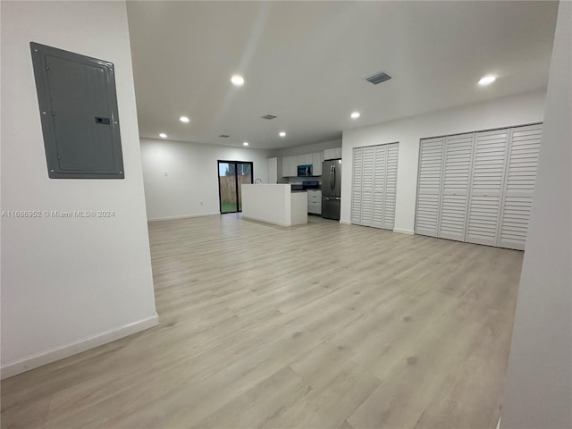 unfurnished living room featuring electric panel and light wood-type flooring