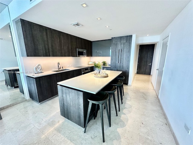 kitchen with a breakfast bar, a center island, dark brown cabinetry, and sink