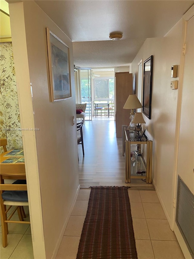 hallway with a textured ceiling and light wood-type flooring