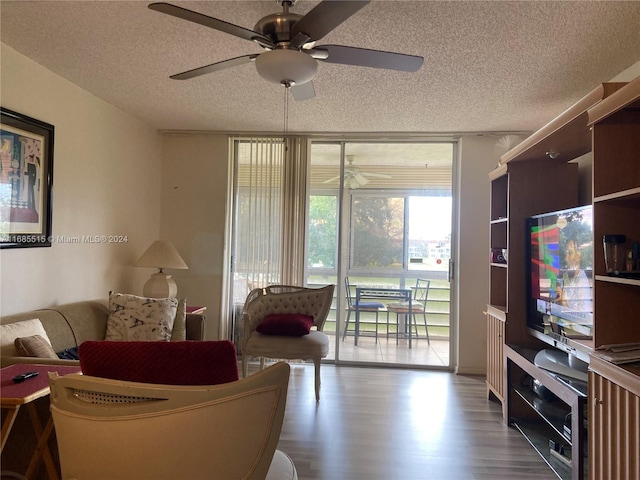 living room with a textured ceiling, wood-type flooring, and ceiling fan