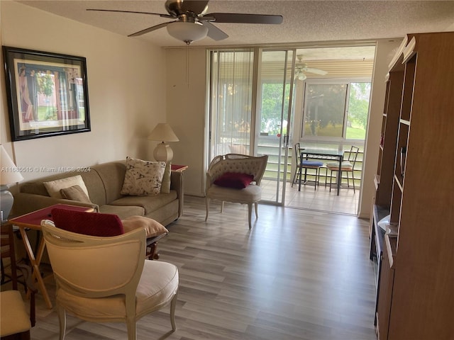 living room featuring ceiling fan, wood-type flooring, and a textured ceiling