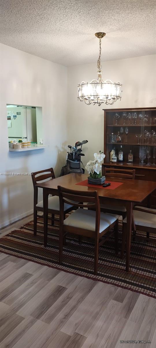 dining space featuring an inviting chandelier, hardwood / wood-style floors, and a textured ceiling