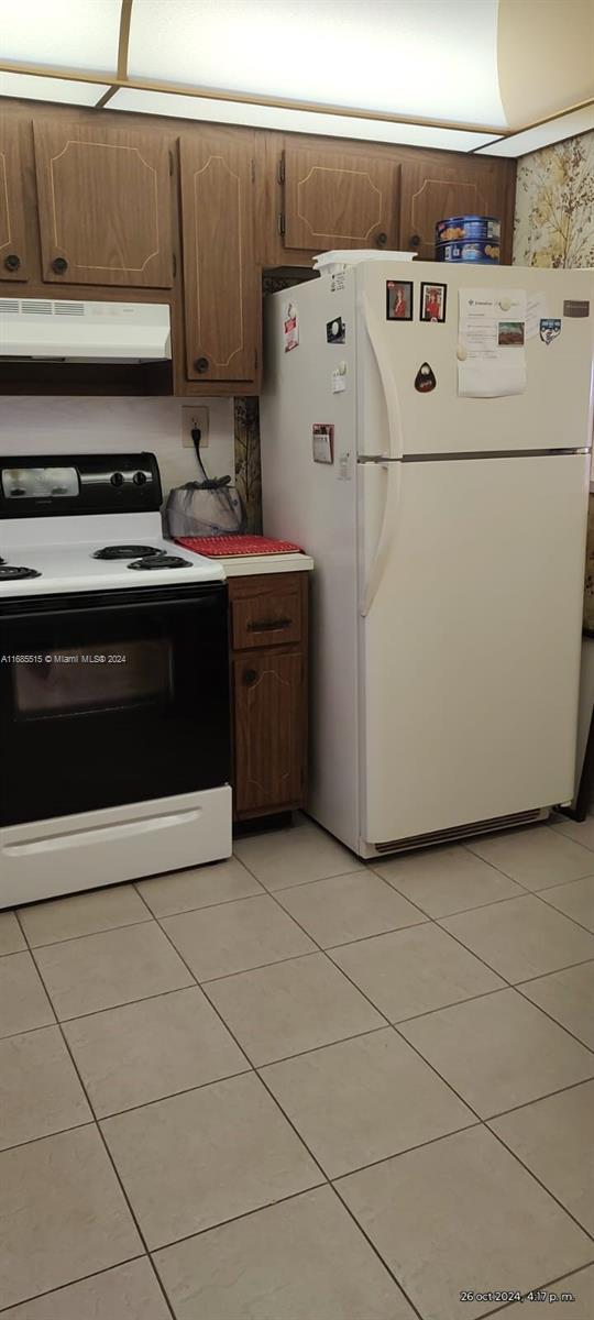 kitchen featuring light tile patterned flooring and white appliances