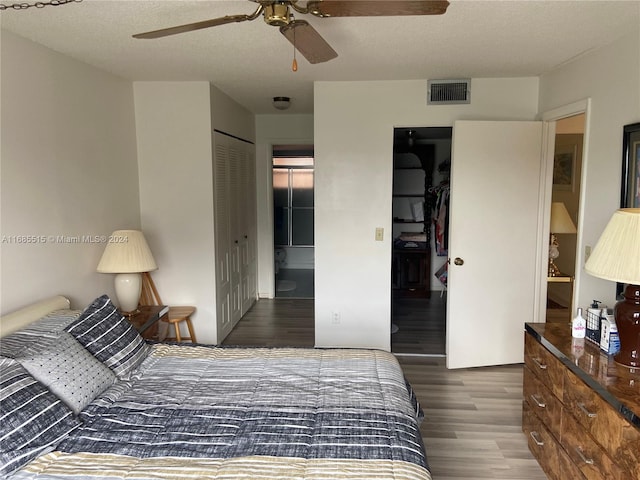 bedroom featuring dark hardwood / wood-style flooring, a closet, a textured ceiling, and ceiling fan