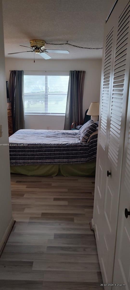 bedroom with a textured ceiling, hardwood / wood-style flooring, and ceiling fan