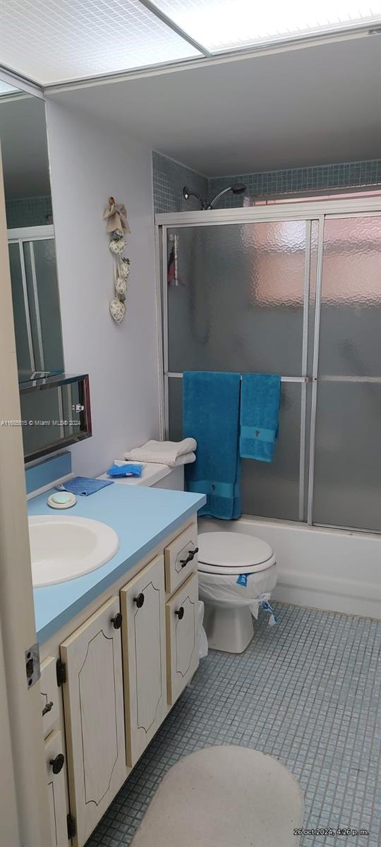 full bathroom featuring vanity, enclosed tub / shower combo, and toilet