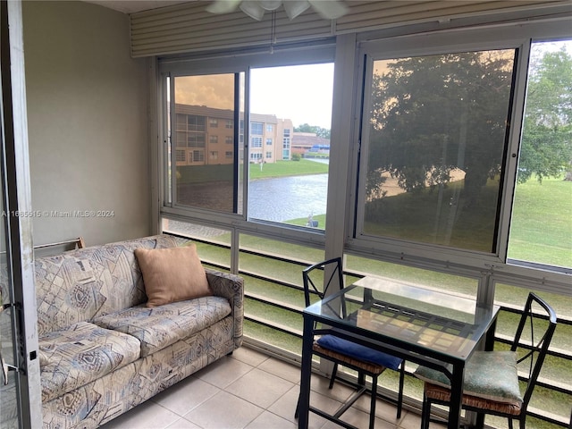 sunroom / solarium with a water view, ceiling fan, and a wealth of natural light