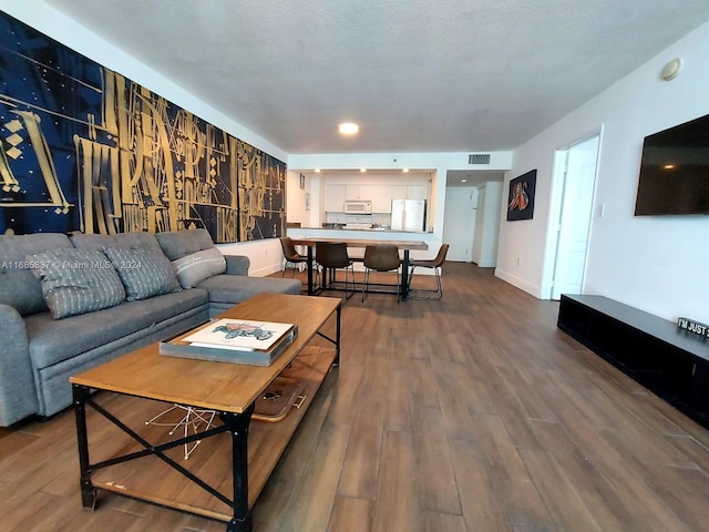 living room with a textured ceiling and dark hardwood / wood-style flooring