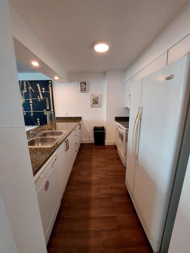 kitchen featuring dark wood-type flooring, dark stone counters, white cabinets, sink, and white appliances