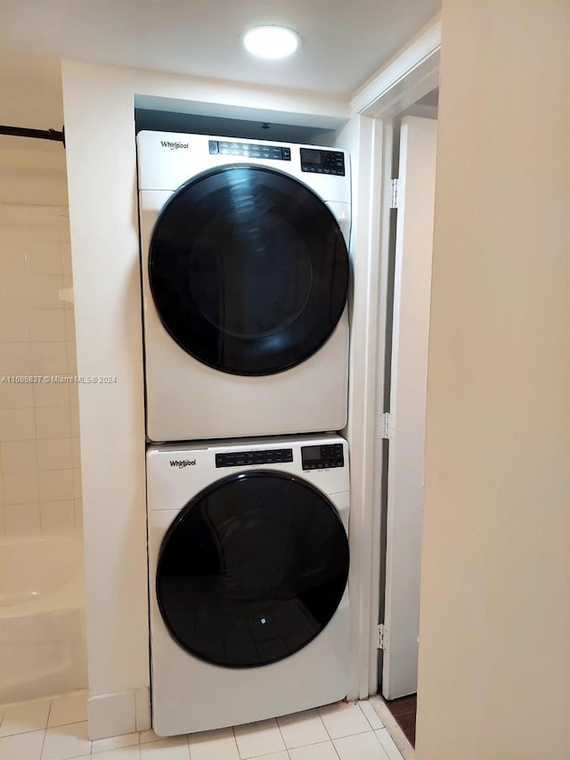 laundry room with light tile patterned floors and stacked washer / dryer