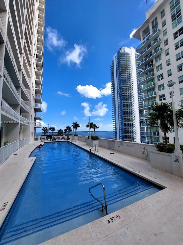 view of pool featuring a water view and a patio area