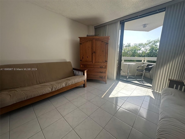 sitting room with light tile patterned floors, a textured ceiling, and a wall of windows