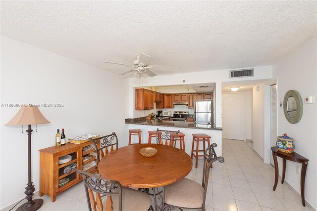 tiled dining space with ceiling fan, floor to ceiling windows, and a textured ceiling