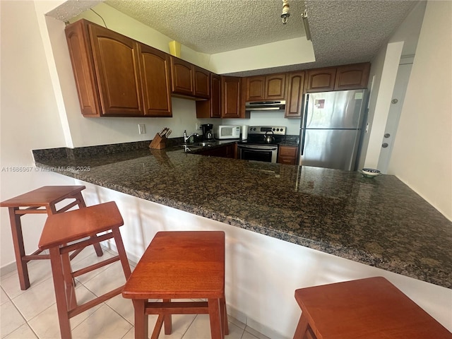 kitchen with stainless steel appliances, sink, light tile patterned floors, and a textured ceiling