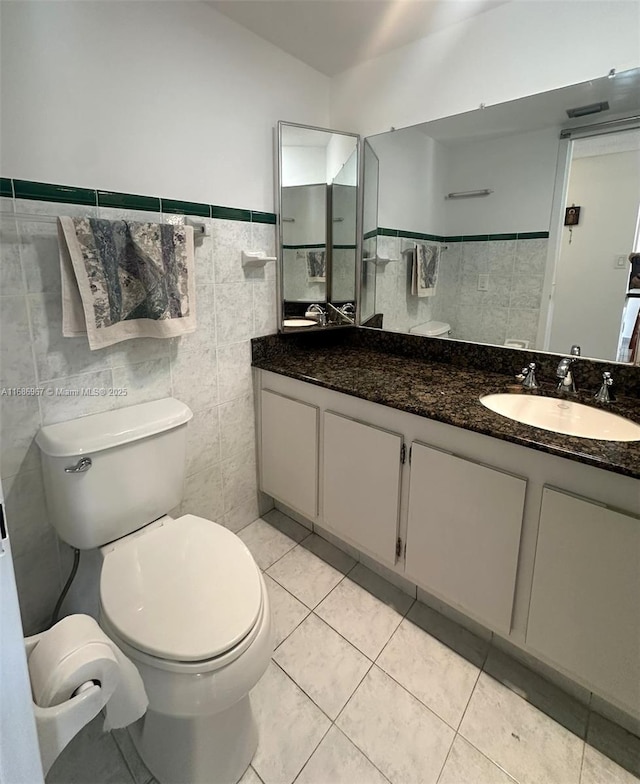 bathroom with vanity, toilet, tile patterned flooring, and tile walls