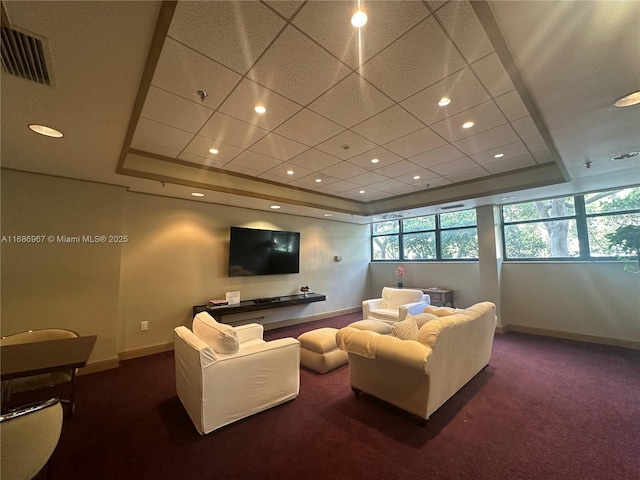 home theater room with a tray ceiling and dark carpet