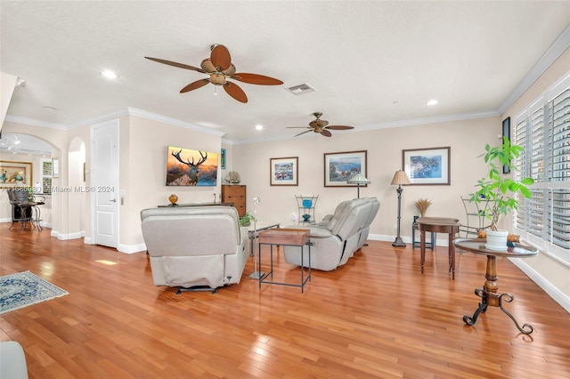 living room with ceiling fan, ornamental molding, a textured ceiling, and light wood-type flooring