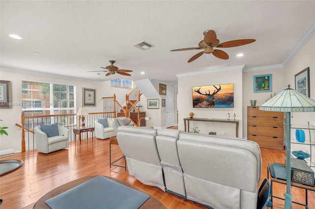 living room featuring crown molding, light hardwood / wood-style flooring, a textured ceiling, and ceiling fan