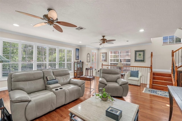 living room featuring crown molding, a textured ceiling, light wood-type flooring, and ceiling fan