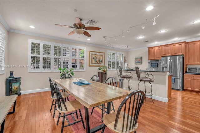 dining space with rail lighting, light hardwood / wood-style floors, ornamental molding, and ceiling fan