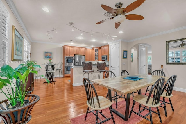 dining area with light hardwood / wood-style flooring, ceiling fan, track lighting, and crown molding