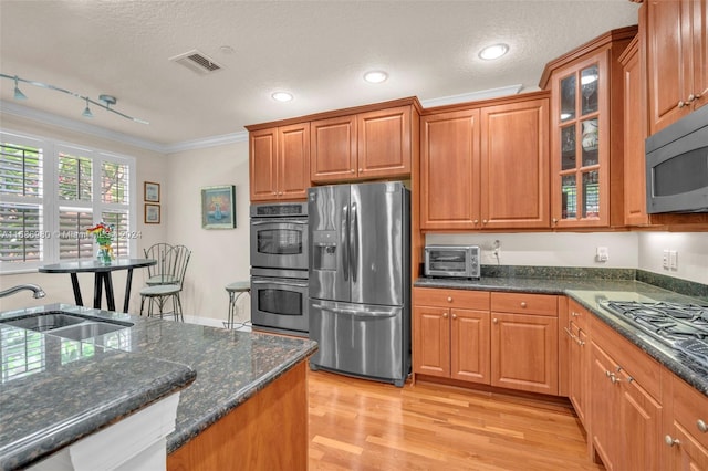 kitchen with sink, a textured ceiling, stainless steel appliances, crown molding, and light hardwood / wood-style flooring