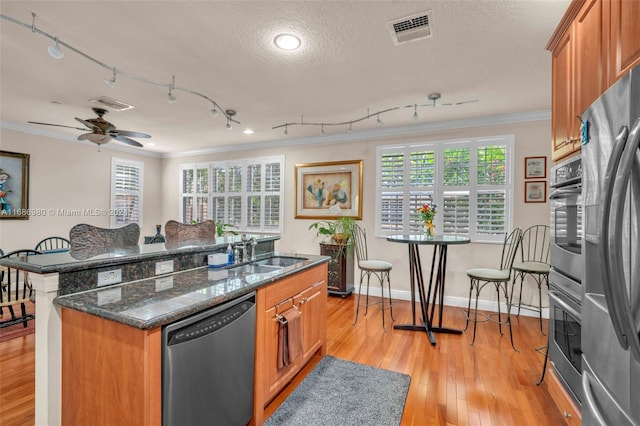 kitchen featuring a kitchen island, crown molding, light wood-type flooring, appliances with stainless steel finishes, and a textured ceiling