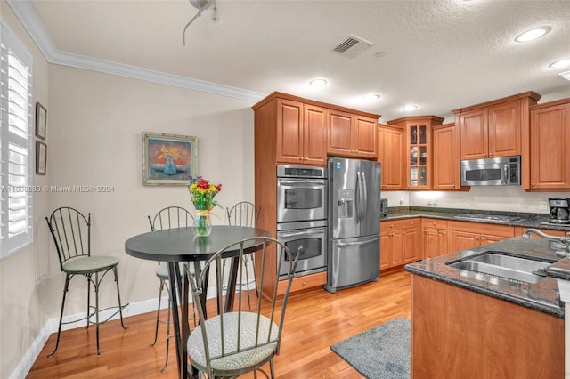 kitchen with sink, stainless steel appliances, ornamental molding, and a wealth of natural light