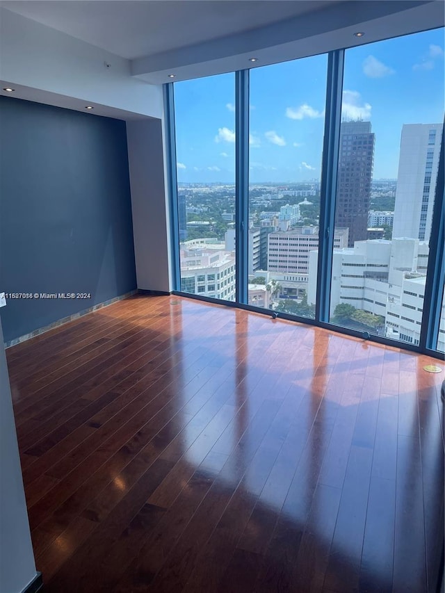 unfurnished room featuring a wall of windows and wood-type flooring