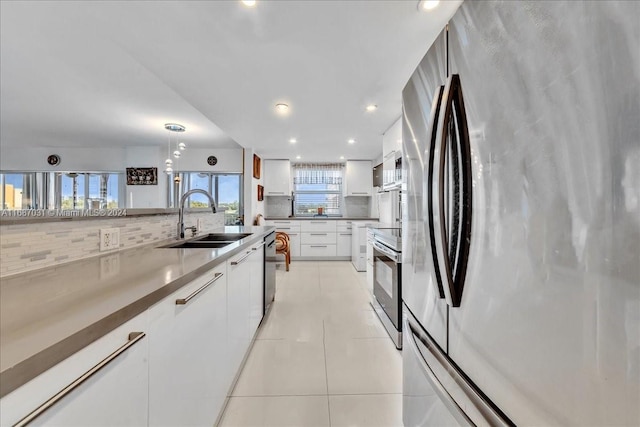 kitchen featuring stainless steel appliances, sink, decorative light fixtures, white cabinets, and tasteful backsplash