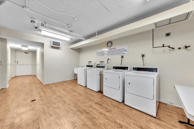 clothes washing area featuring washer and clothes dryer, a textured ceiling, and light wood-type flooring