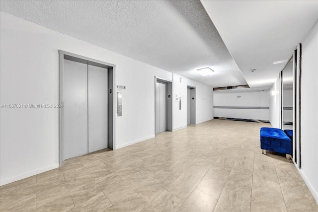 hallway with a textured ceiling and elevator