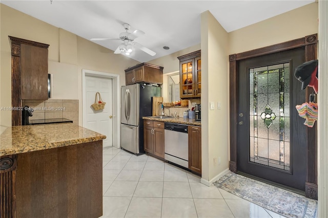 kitchen with tasteful backsplash, light tile patterned flooring, appliances with stainless steel finishes, light stone countertops, and ceiling fan