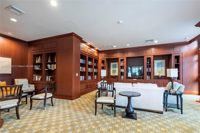 living room with wooden walls, built in features, and crown molding