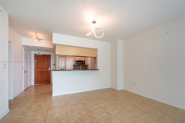 unfurnished living room featuring a notable chandelier and light tile patterned flooring