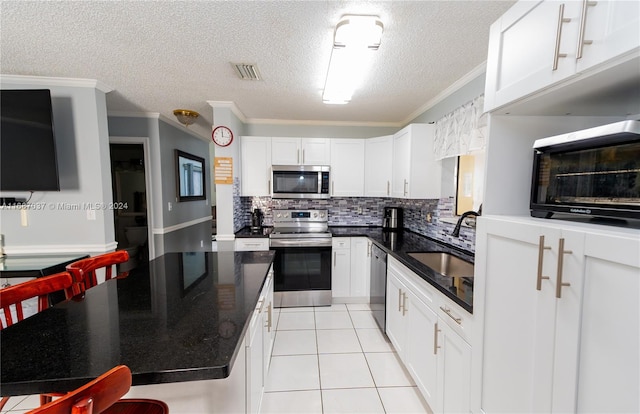 kitchen with stainless steel appliances, ornamental molding, sink, light tile patterned flooring, and white cabinets